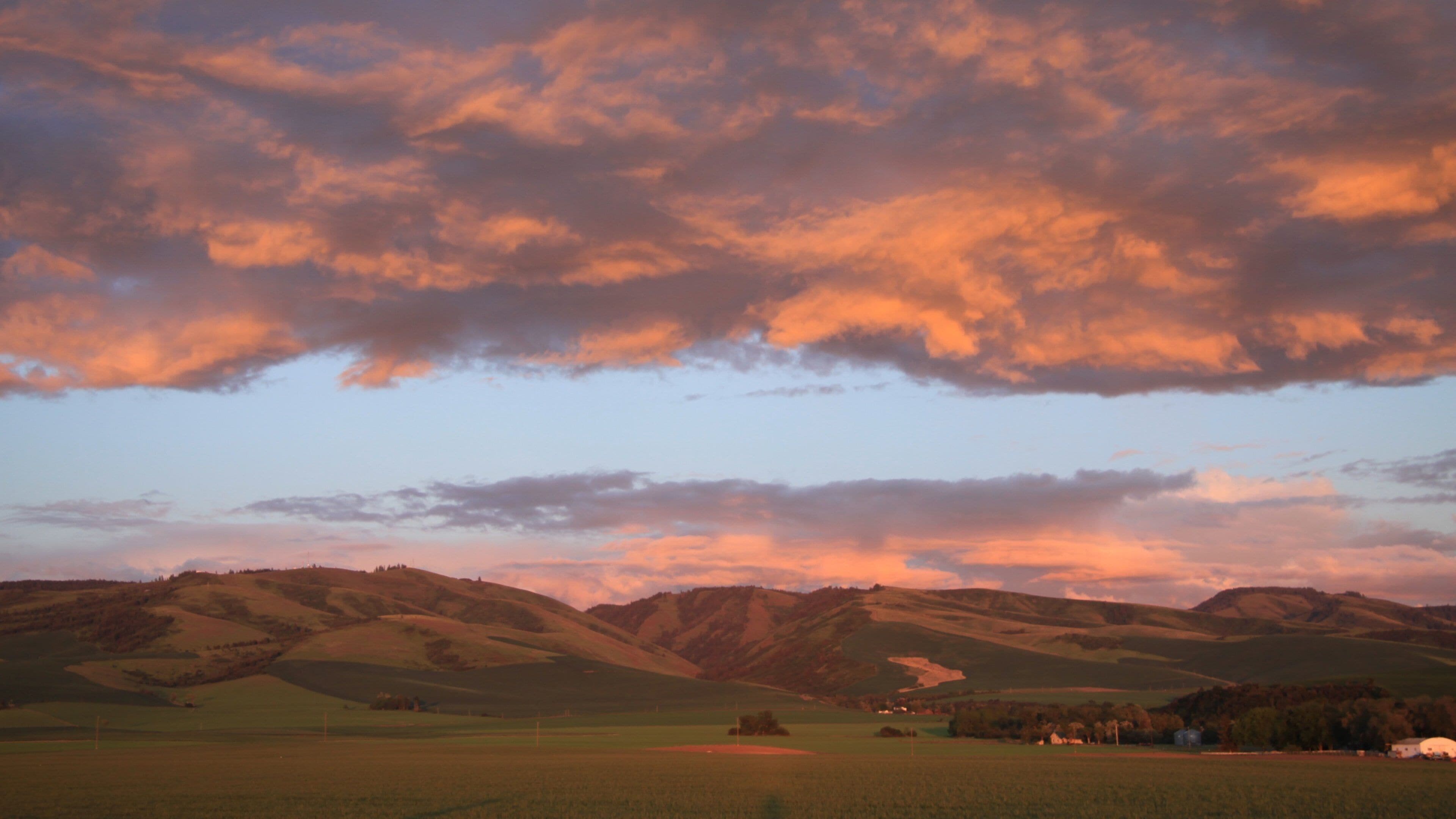 Rolling hills, a field, and a distant village.