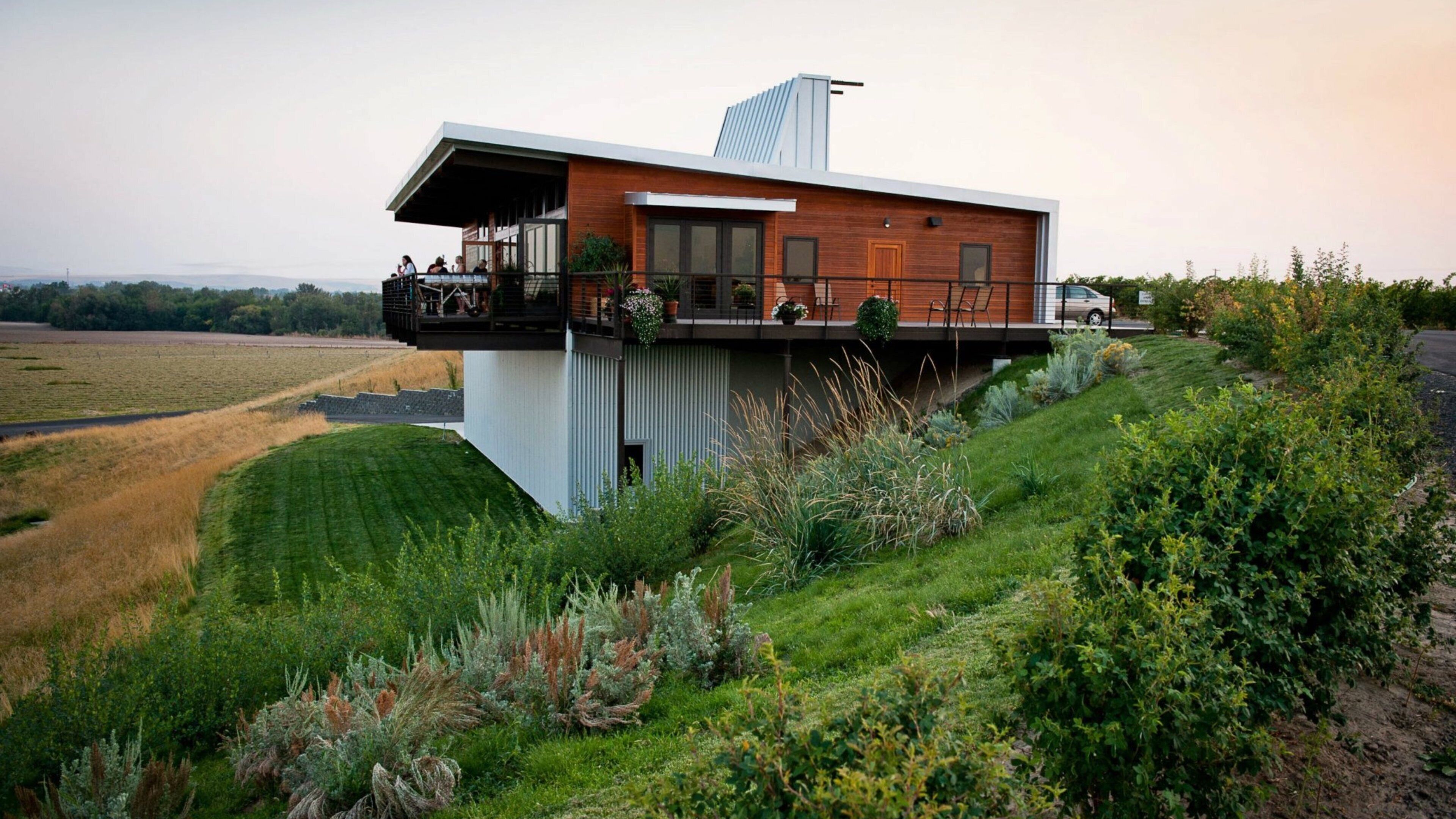 A modern house with a balcony overlooking a grassy field.