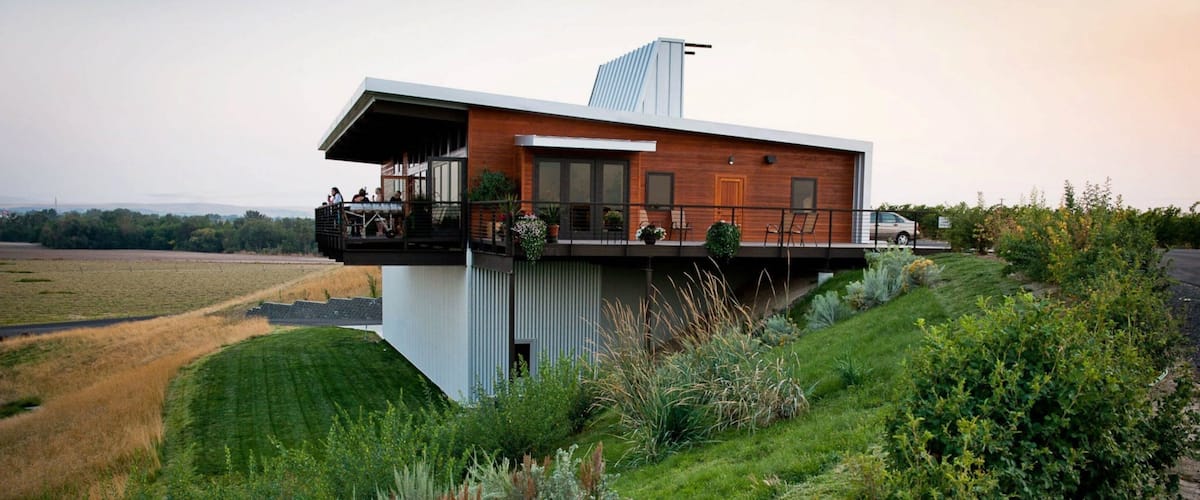 A modern house with a balcony overlooking a grassy field.
