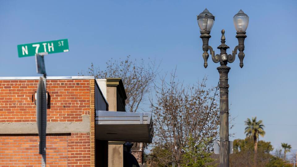 A street sign for N 7TH ST, a brick building, and a street lamp.