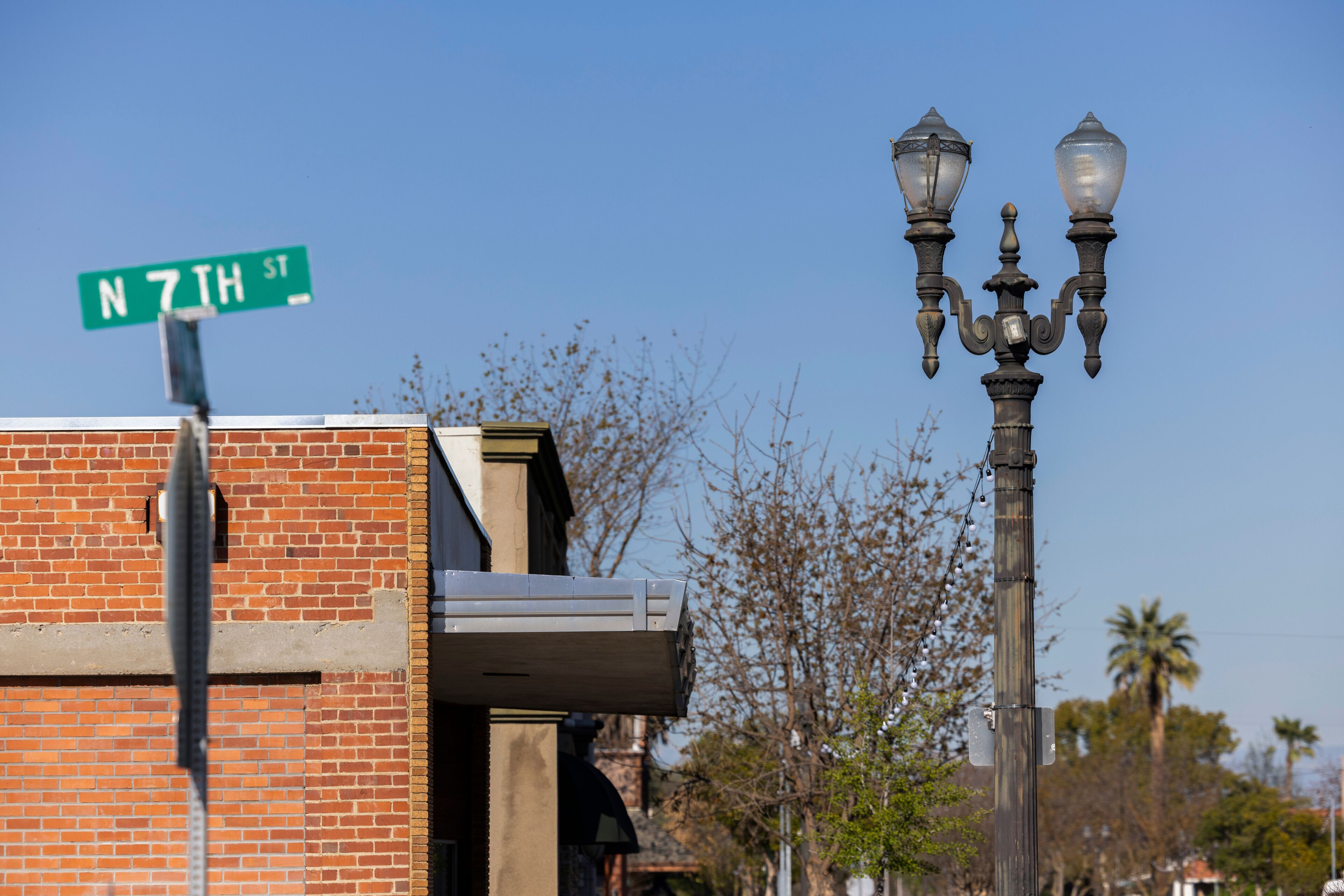 A street sign for N 7TH ST, a brick building, and a street lamp.