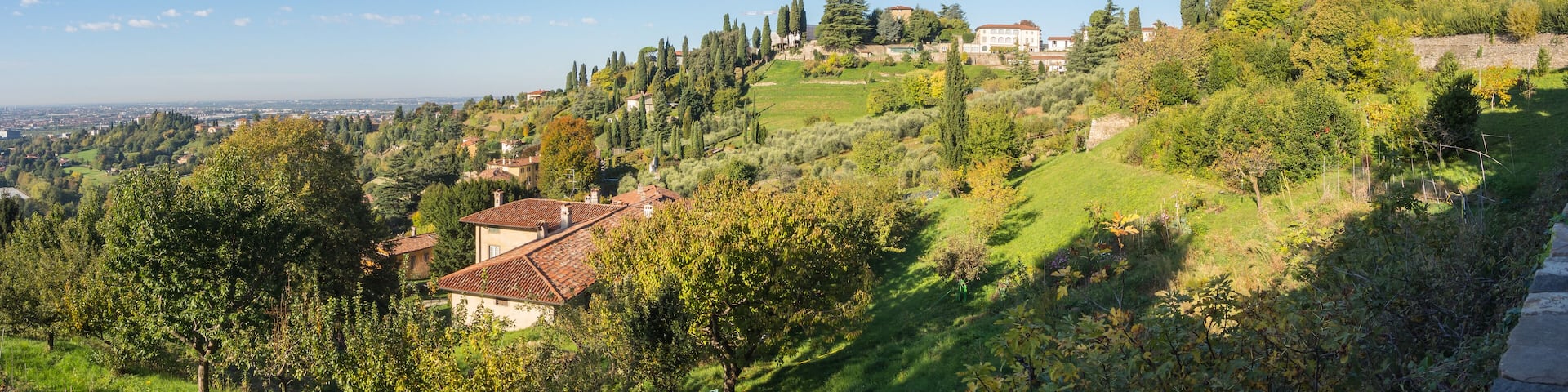 A hillside village with terraced fields, traditional houses, and a prominent church tower.