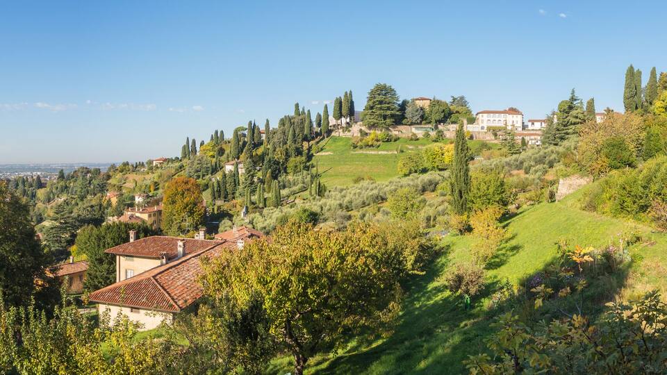 A hillside village with terraced fields, traditional houses, and a prominent church tower.