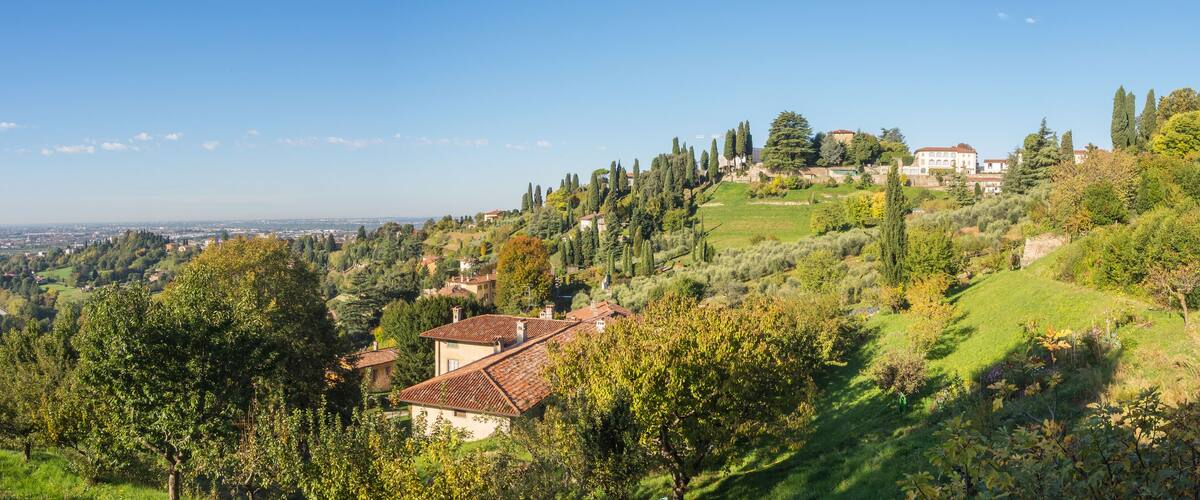 A hillside village with terraced fields, traditional houses, and a prominent church tower.