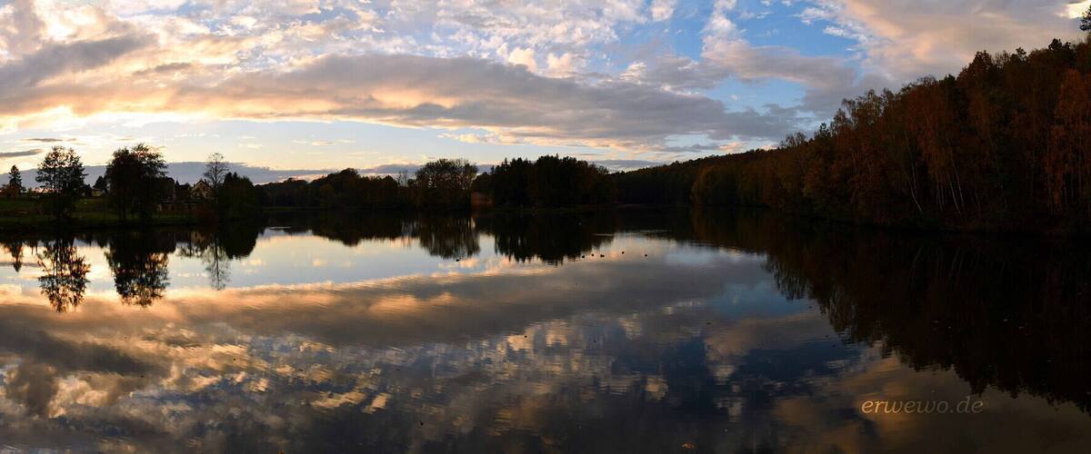 A calm lake reflecting the sky and trees.