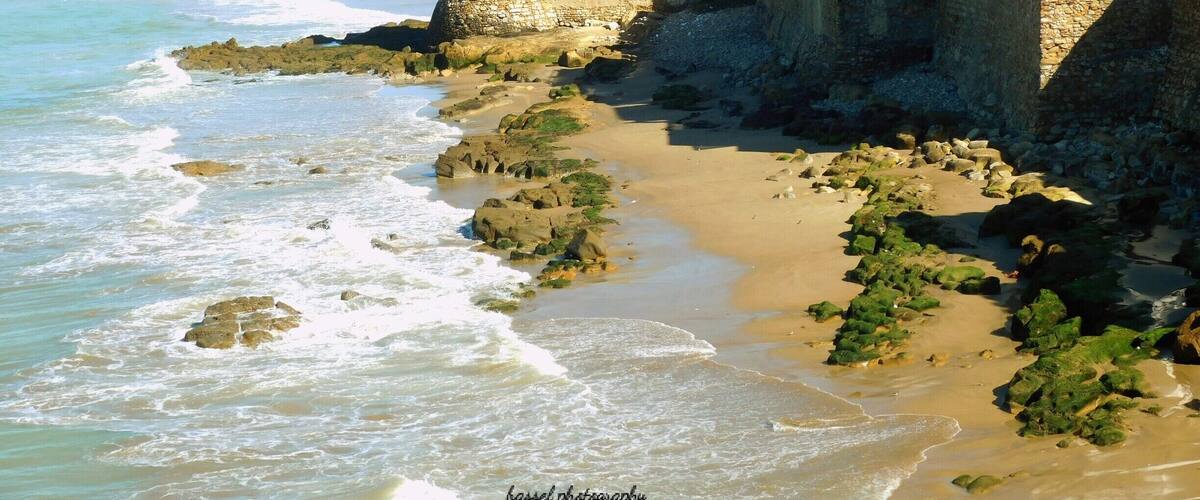 Asilah (Arabic: أصيلة، Aṣīla; Berber: ⴰⵥⵉⵍⴰ Aẓila; "authentic", Portuguese: Arzila, Spanish: Arcila) is a fortified town on the northwest tip of the Atlantic coast of Morocco, about 31 km (19 mi) south of Tangier. Its ramparts and gateworks remain fully intact.
The town's history dates back to 1500 B.C., when the Phoenicians used it as a base for trade. The Portuguese conquered the city in 1471, but later it was decided to abandon it because of an economic debt crisis in 1549. Later in 1578, Sebastian of Portugal used Asilah as a base town for his troops during a planned crusade that resulted in Sebastian's death, which in turn caused the Portuguese succession crisis of 1580. The Moroccans in 1589 regained control of Asilah briefly, but then lost control of it to the Spanish.
In 1692, the town was again taken by the Moroccans under the leadership of Moulay Ismail. Asilah served then as a base for pirates in the 19th and 20th centuries, and in 1829, the Austrians punitively bombarded the city due to Moroccan piracy.
From 1912 to 1956, it was part of Spanish Morocco. A major plan to restore the town was undertaken in 1978 by its mayor, Mohamed Benaissa. The first edition of an art festival known as the International Cultural Moussem of Asilah was launched that year to help generate tourism. It was successful in generating revenue for the city and played a role in raising the average monthly income from $50 in 1978 to $140 in 2014. The festival features local artwork and music and continues to attract large amounts of tourists.
Asilah is now a popular seaside resort, with modern holiday apartment complexes on the coast road leading to the town from Tangier.
