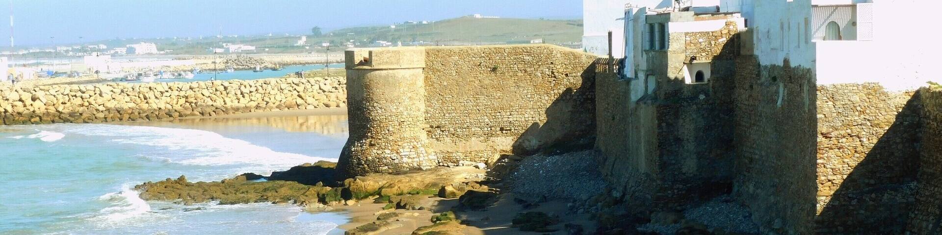 Asilah (Arabic: أصيلة، Aṣīla; Berber: ⴰⵥⵉⵍⴰ Aẓila; "authentic", Portuguese: Arzila, Spanish: Arcila) is a fortified town on the northwest tip of the Atlantic coast of Morocco, about 31 km (19 mi) south of Tangier. Its ramparts and gateworks remain fully intact.
The town's history dates back to 1500 B.C., when the Phoenicians used it as a base for trade. The Portuguese conquered the city in 1471, but later it was decided to abandon it because of an economic debt crisis in 1549. Later in 1578, Sebastian of Portugal used Asilah as a base town for his troops during a planned crusade that resulted in Sebastian's death, which in turn caused the Portuguese succession crisis of 1580. The Moroccans in 1589 regained control of Asilah briefly, but then lost control of it to the Spanish.
In 1692, the town was again taken by the Moroccans under the leadership of Moulay Ismail. Asilah served then as a base for pirates in the 19th and 20th centuries, and in 1829, the Austrians punitively bombarded the city due to Moroccan piracy.
From 1912 to 1956, it was part of Spanish Morocco. A major plan to restore the town was undertaken in 1978 by its mayor, Mohamed Benaissa. The first edition of an art festival known as the International Cultural Moussem of Asilah was launched that year to help generate tourism. It was successful in generating revenue for the city and played a role in raising the average monthly income from $50 in 1978 to $140 in 2014. The festival features local artwork and music and continues to attract large amounts of tourists.
Asilah is now a popular seaside resort, with modern holiday apartment complexes on the coast road leading to the town from Tangier.