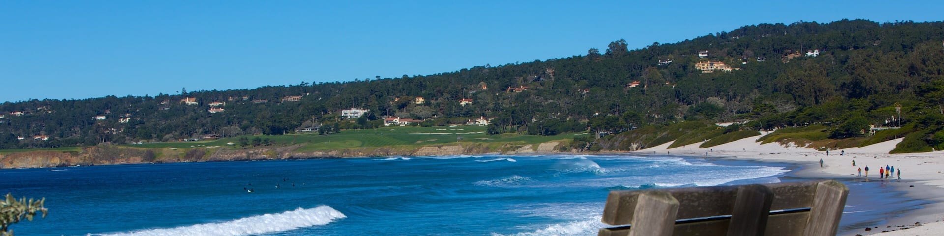 A wooden chair overlooking a beach with waves crashing onto the shore.