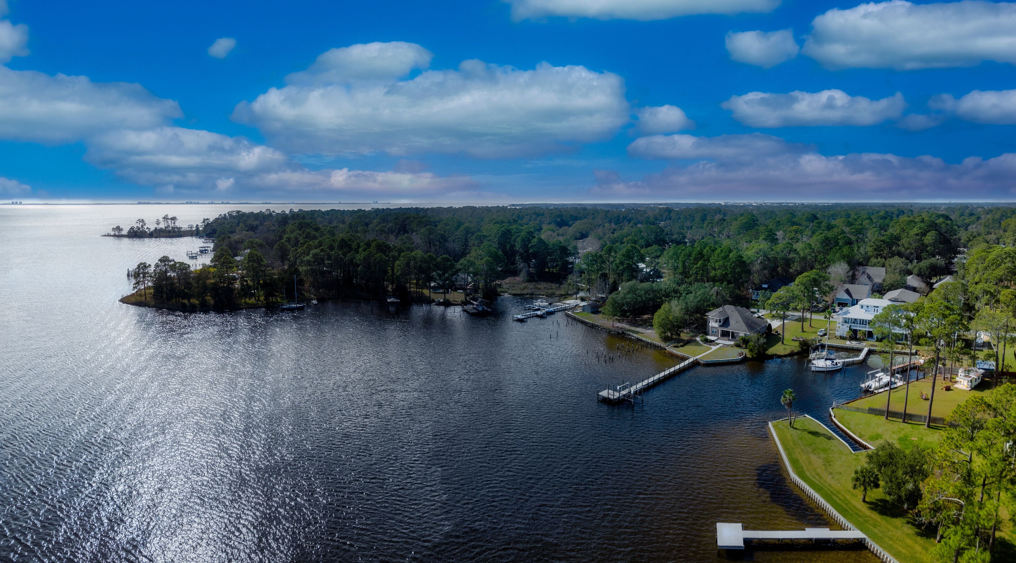 A lake with a dock, surrounded by trees and houses.