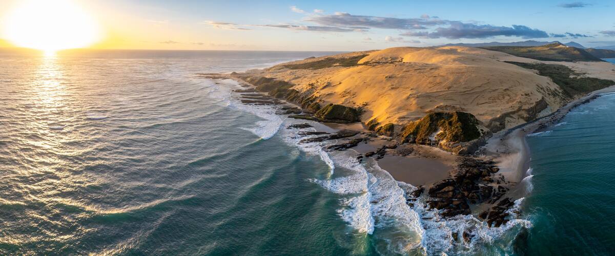 A coastal landscape with a sandy island surrounded by turquoise waters.