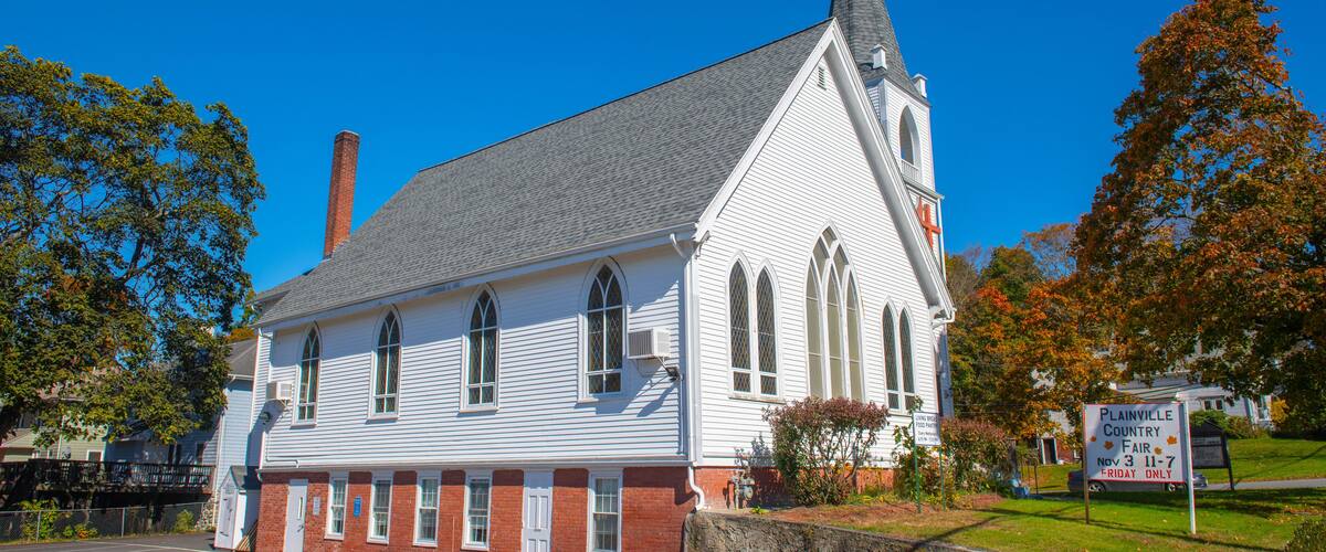 A white church with a steeple and a parking lot.