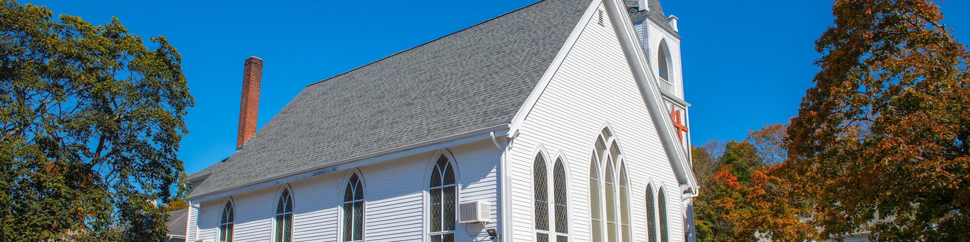 A white church with a steeple and a parking lot.