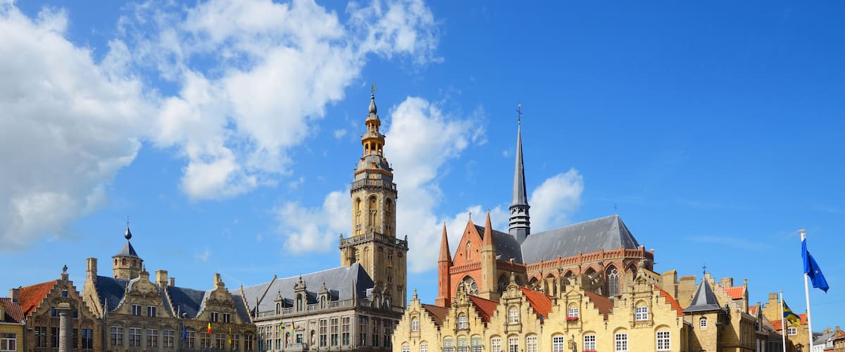 A historic building with a tall tower and a spire, under a clear blue sky.