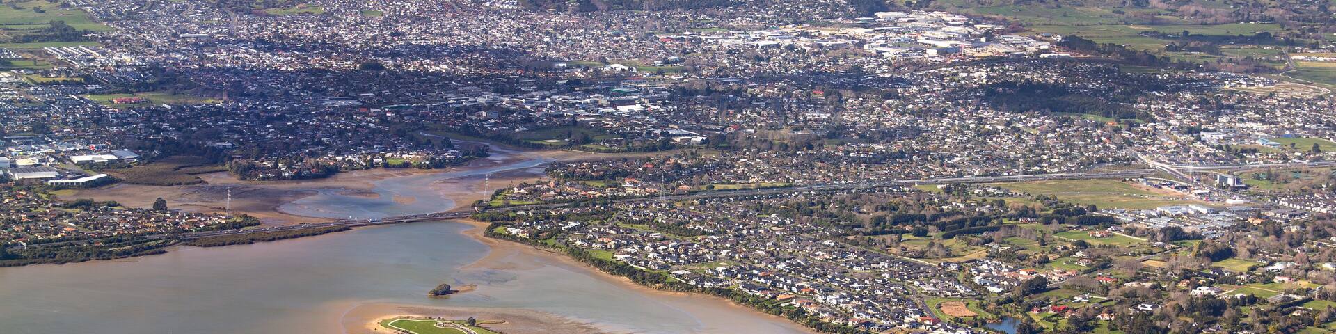 Pararekau Island and Manukau Harbour, Auckland, New Zealand, aerial view. Development in 2025 of gated exclusive subdivision on the island. Motorway, Karaka, Papakura, Takanini and Ardmore in distance