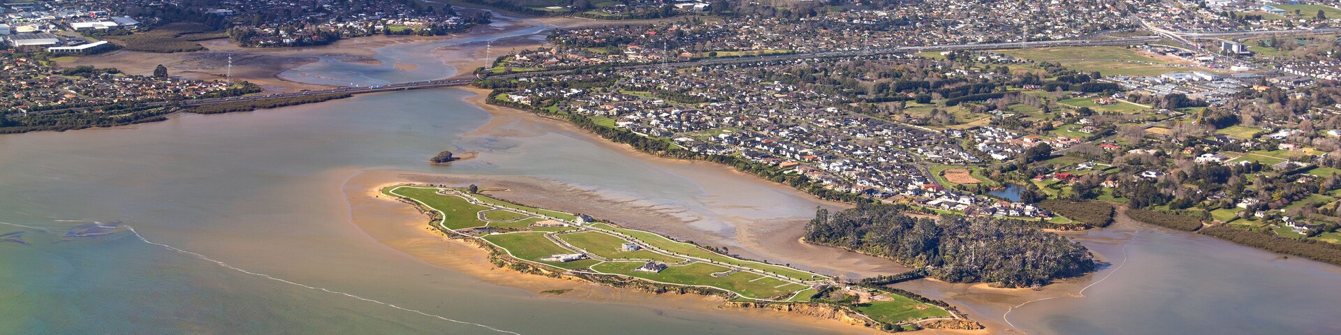 Pararekau Island and Manukau Harbour, Auckland, New Zealand, aerial view. Development in 2025 of gated exclusive subdivision on the island. Motorway, Karaka, Papakura, Takanini and Ardmore in distance