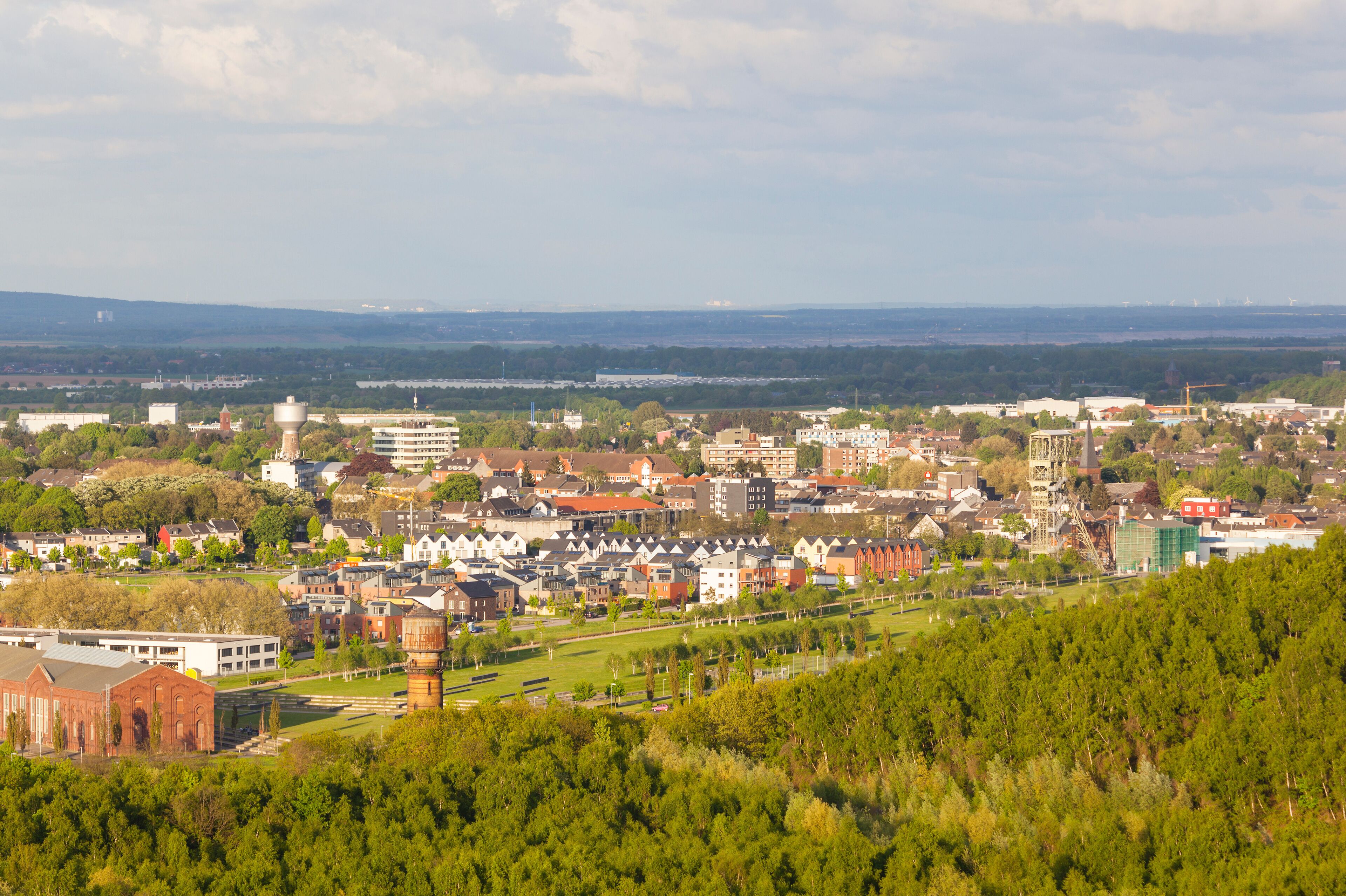 A cityscape with a mix of residential and commercial buildings, a prominent water tower, and a distant view of a river.