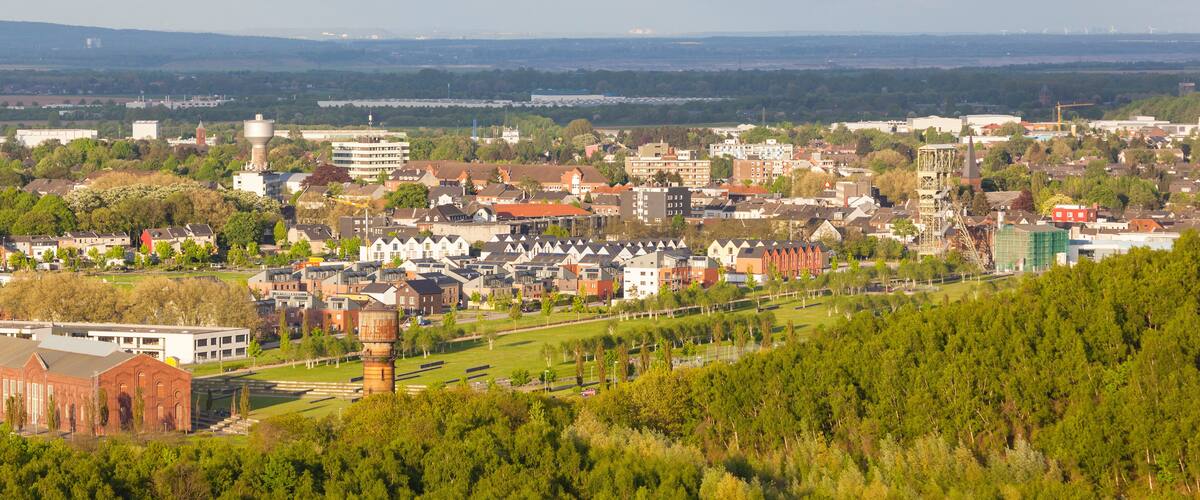 A cityscape with a mix of residential and commercial buildings, a prominent water tower, and a distant view of a river.