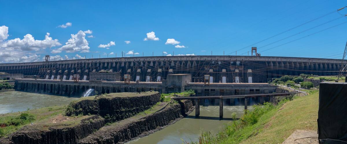 A large dam with multiple spillways and a river flowing below.