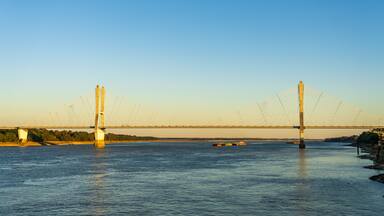 Uma ponte suspensa sobre um rio, com um navio de carga na água.