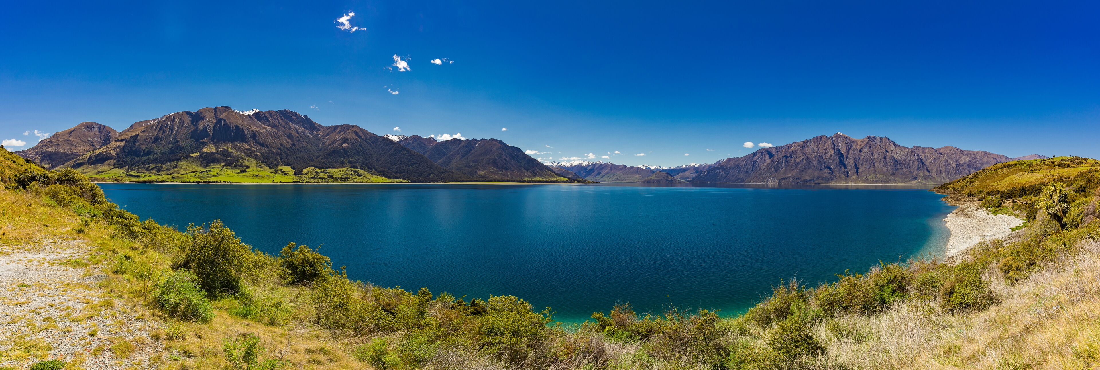 A lake surrounded by mountains and greenery.