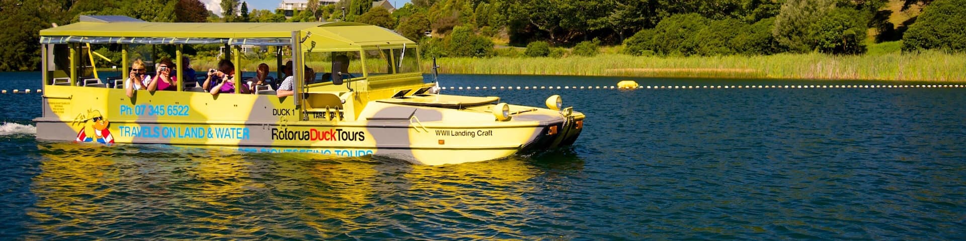 A yellow boat with passengers on a lake surrounded by greenery.