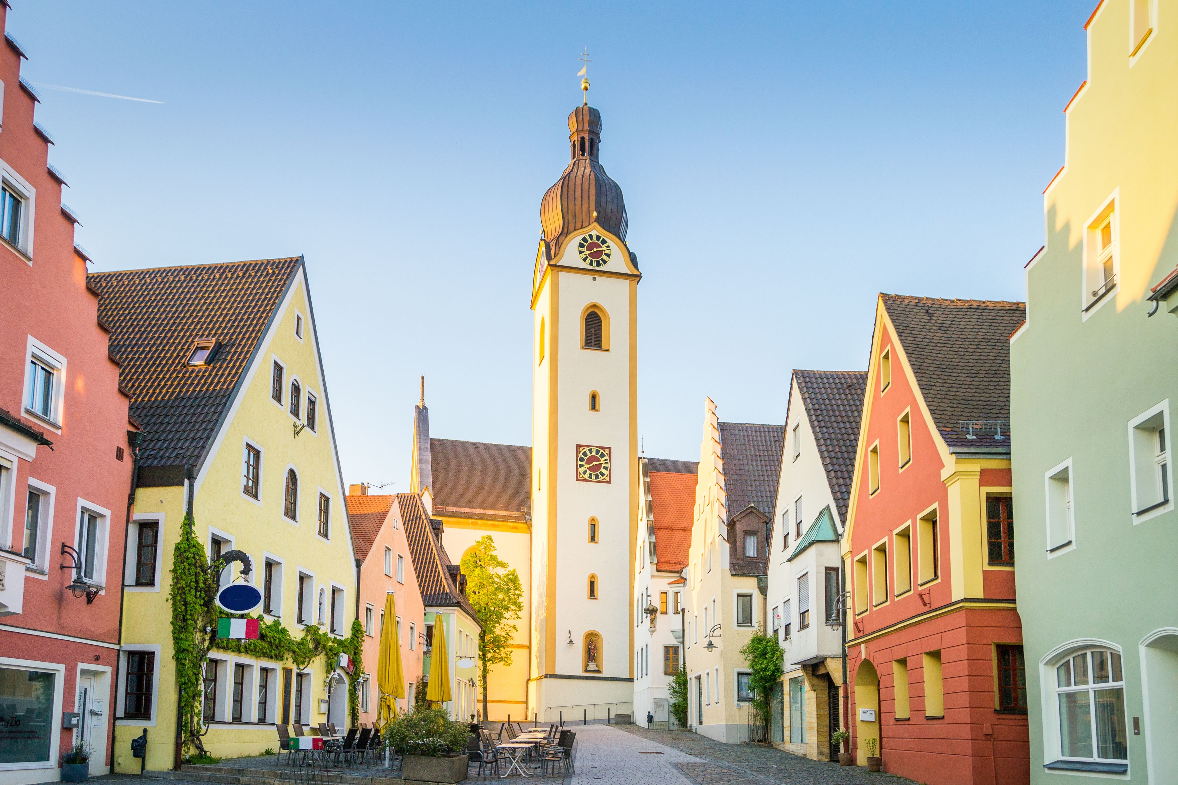 Une place historique, bordée de bâtiments aux couleurs vives, avec un imposant beffroi et des rues pavées.
