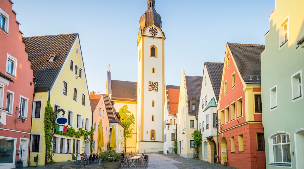 Une place historique, bordée de bâtiments aux couleurs vives, avec un imposant beffroi et des rues pavées.