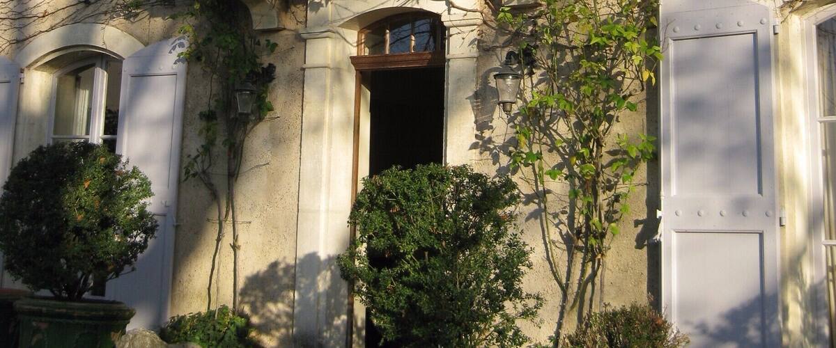 A historic stone building with a balcony, potted plants, and a door.