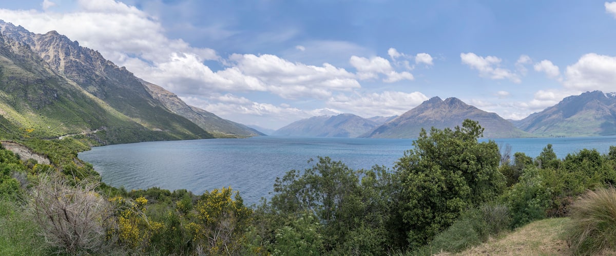 A mountainous landscape with a lake surrounded by greenery and trees.