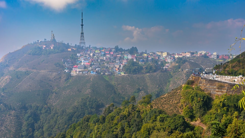 A mountainous town with colorful buildings, a prominent tower, and lush greenery.