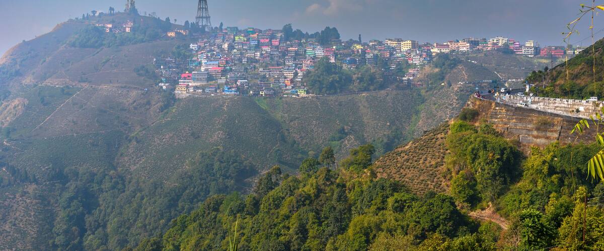 A mountainous town with colorful buildings, a prominent tower, and lush greenery.