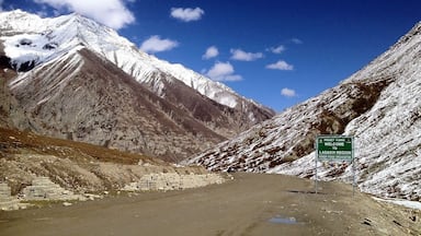 Una carretera que conduce a una cordillera nevada, con un letrero que da la bienvenida a la región de Ladakh.