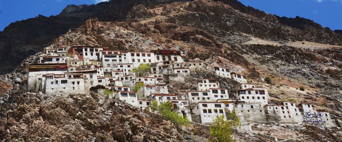 A cluster of white buildings on a rocky hillside under a clear blue sky.