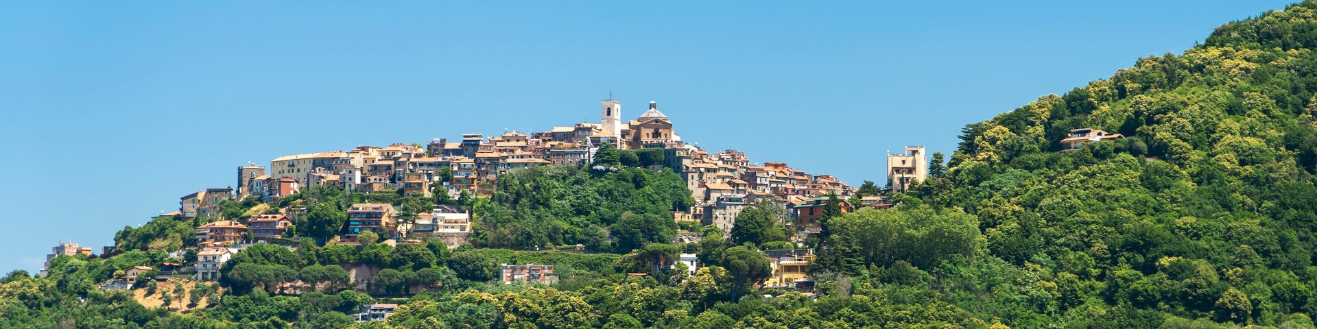 A densely packed hillside town with historic buildings and a prominent church on top.
