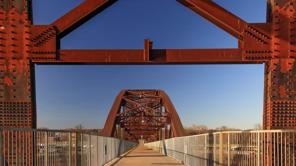 A large, rusted metal bridge with a metal walkway and railings.