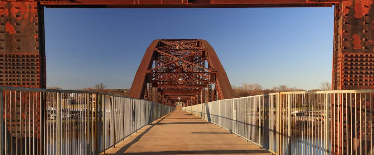 A large, rusted metal bridge with a metal walkway and railings.
