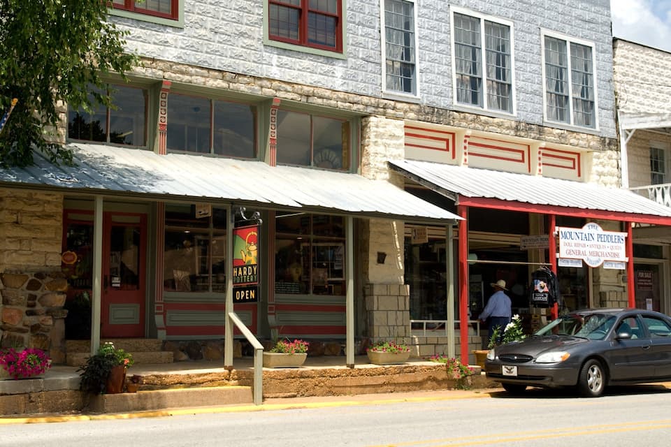 A storefront with a sign reading "Mountain Peddlers" and a man standing outside.