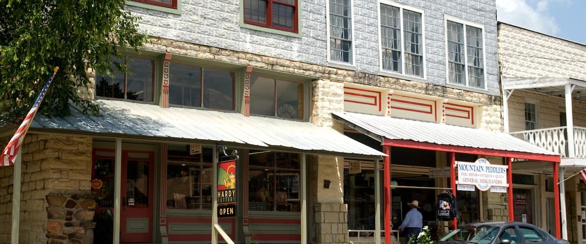 A storefront with a sign reading "Mountain Peddlers" and a man standing outside.