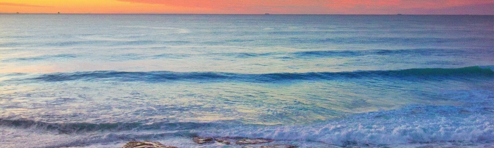 Una costa rocosa con olas al atardecer.