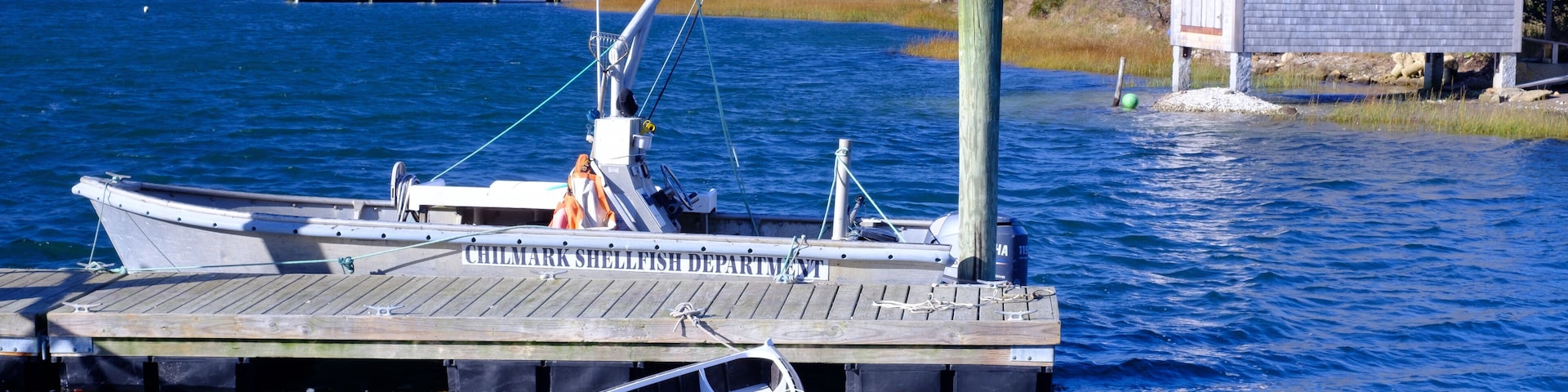 A dock with boats, a small wooden structure, and a forested shoreline.