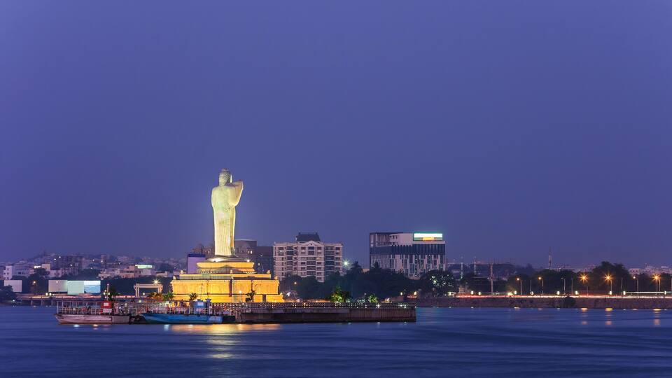 A large illuminated monument by a body of water at dusk.