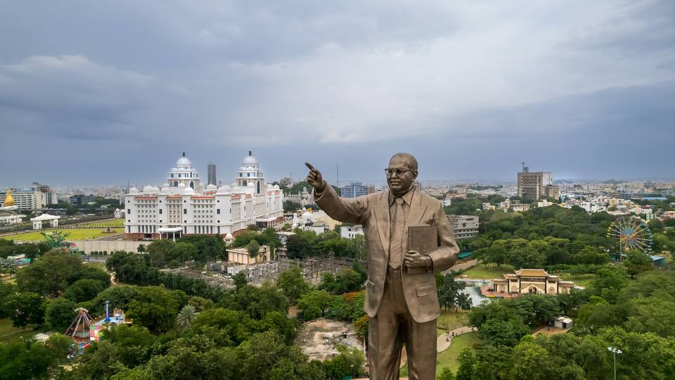 A statue of a man in a suit with a cityscape in the background.