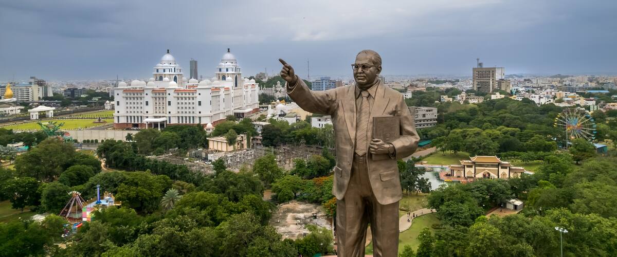 A statue of a man in a suit with a cityscape in the background.