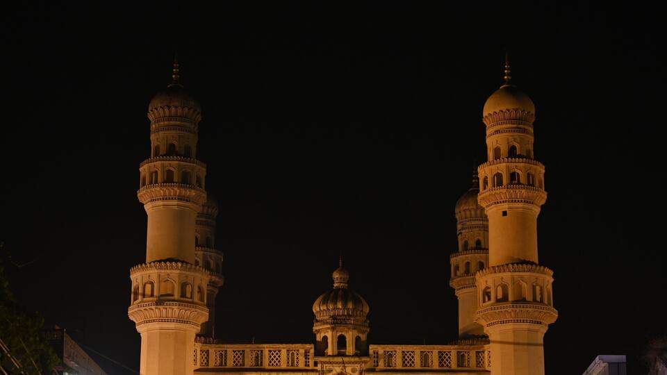 Una gran mezquita iluminada con dos imponentes minaretes y una cúpula central.