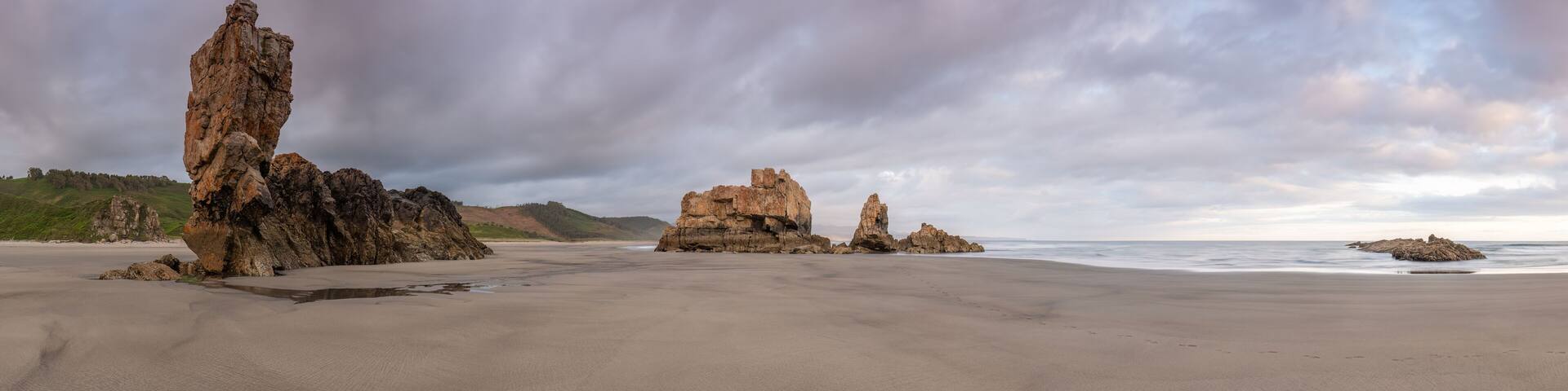 A coastal landscape with prominent rock formations and a beach.