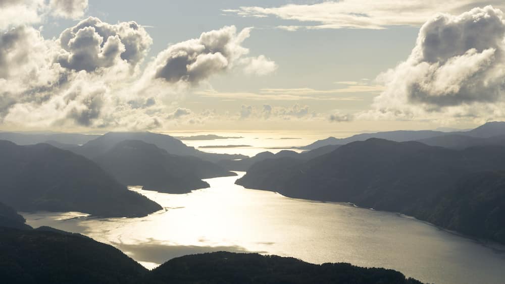 Amazing panoramic sunset view from Hellandsnuten Mountain to mountain ranges silhouettes and Sandsfjord and the Ocean. Norway.