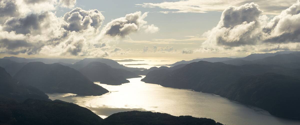 Amazing panoramic sunset view from Hellandsnuten Mountain to mountain ranges silhouettes and Sandsfjord and the Ocean. Norway.