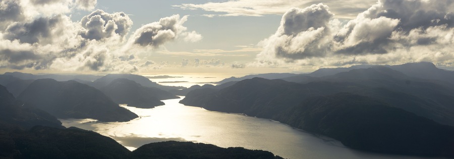 Amazing panoramic sunset view from Hellandsnuten Mountain to mountain ranges silhouettes and Sandsfjord and the Ocean. Norway.
