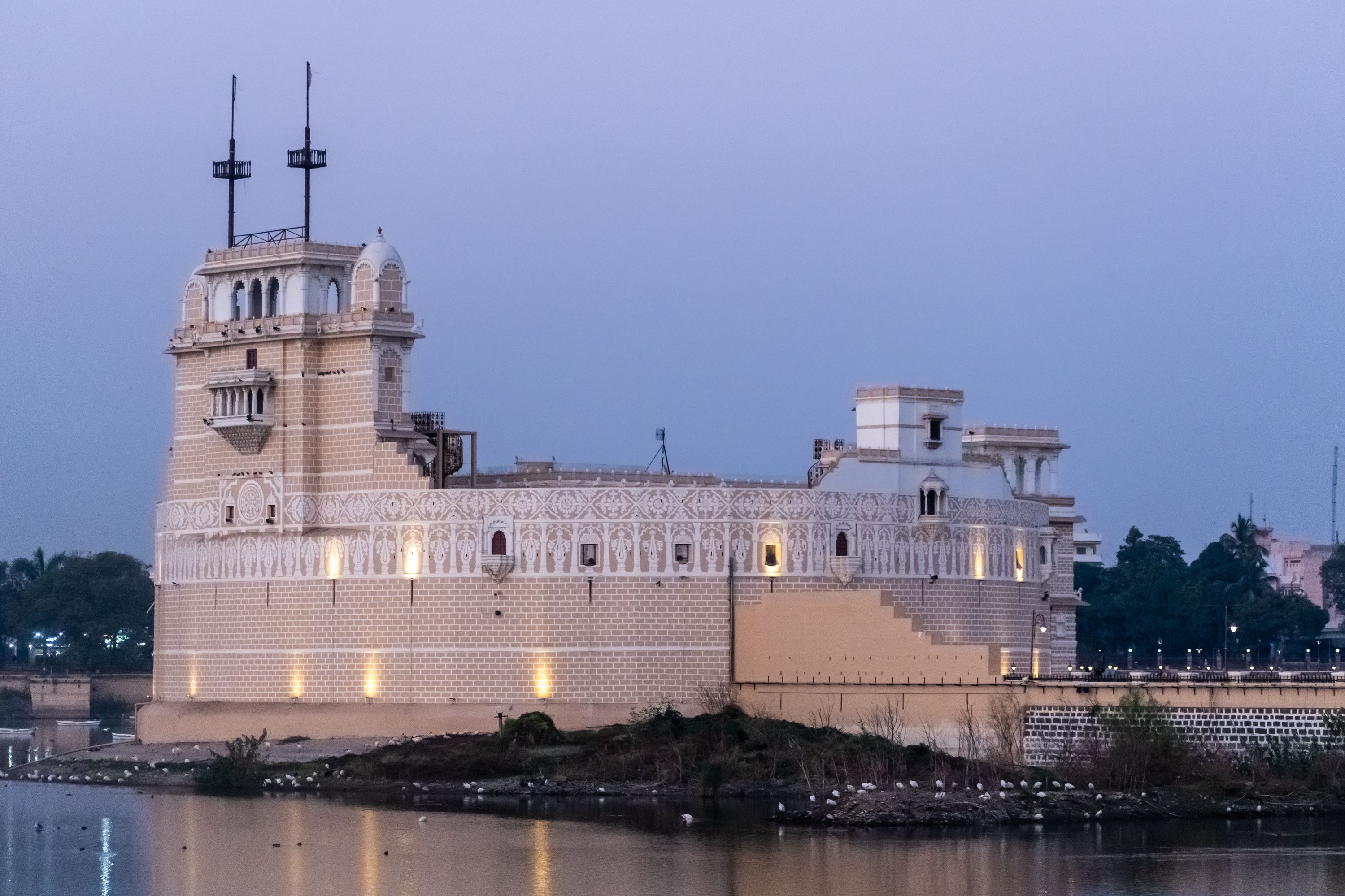 A large, ornate building with intricate architectural details, situated beside a calm body of water.