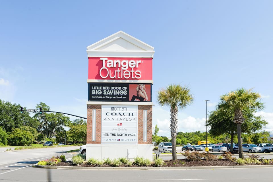 A Tanger Outlets sign with a 'Little Red Book of Big Savings' advertisement.